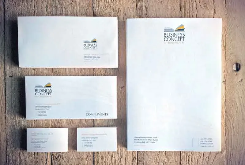 A printed letterhead, envelopes, compliments slip and business cards laid out on a wooden surface