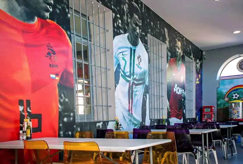 Printed football-shirt wallpaper covering the wall of a sports bar dining room