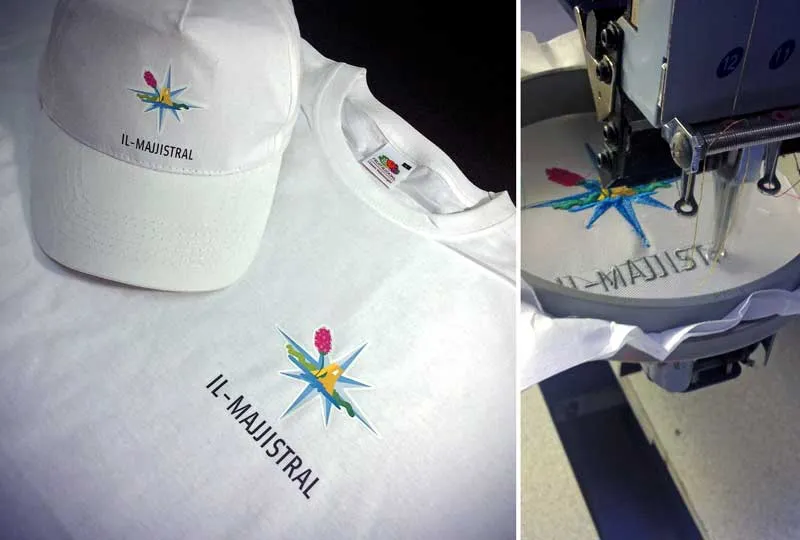 The Il-Majjistral logo embroidered onto a white cap and t-shirt, beside the machine stitching it
