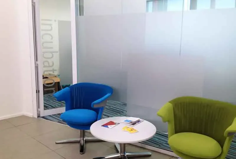 Frosted vinyl panels applied to a glass office partition beside a small waiting area